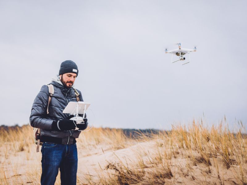 Survey professional operating a drone to collect LiDAR mapping data for terrain analysis on undeveloped land.