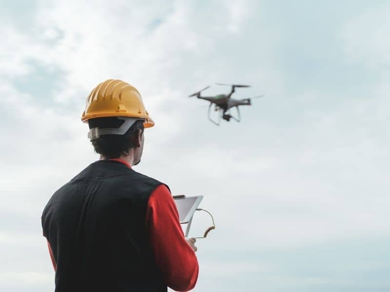Drone mapping specialist gathering terrain data to evaluate ground conditions beneath tree coverage before planning a new home.
