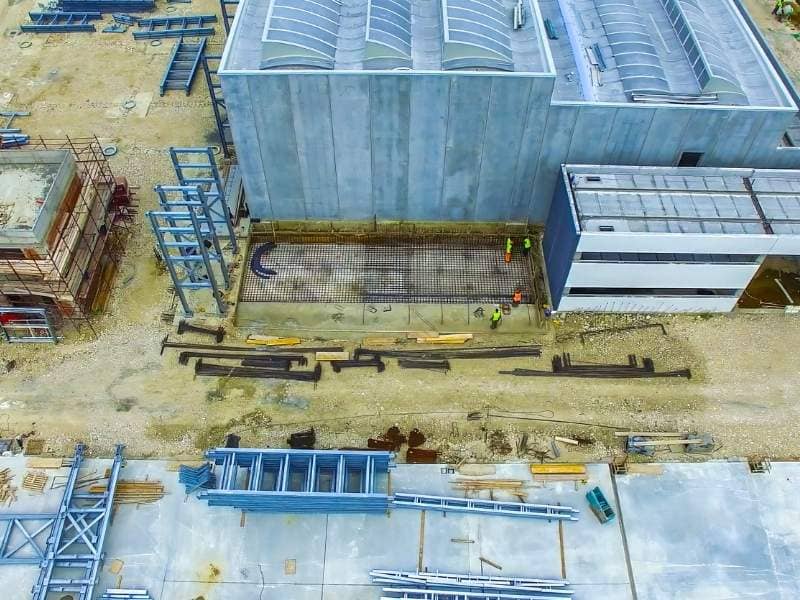 Aerial view of a large industrial construction site showing buildings, foundations, and materials used for land surveying and site analysis in construction planning.
