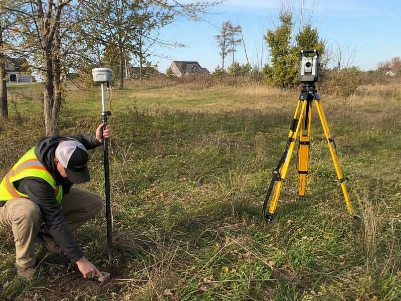Lot surveyor inspecting an old boundary monument on vacant property in Clarksville Tennessee